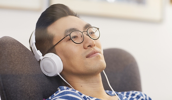 Mann entspannt auf Couch mit Kopfhörern